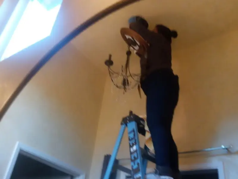 Electrician installing a chandelier in a Oxford residence